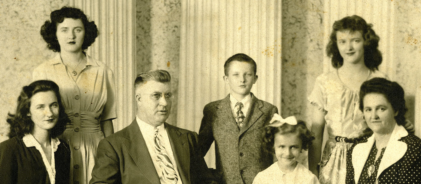 Portrait sépia d’une famille dans un studio; on y voit les deux parents et cinq enfants.
