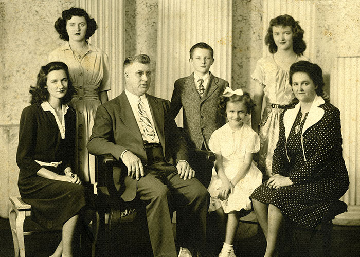 Portrait sépia d’une famille dans un studio; on y voit les deux parents et cinq enfants. 